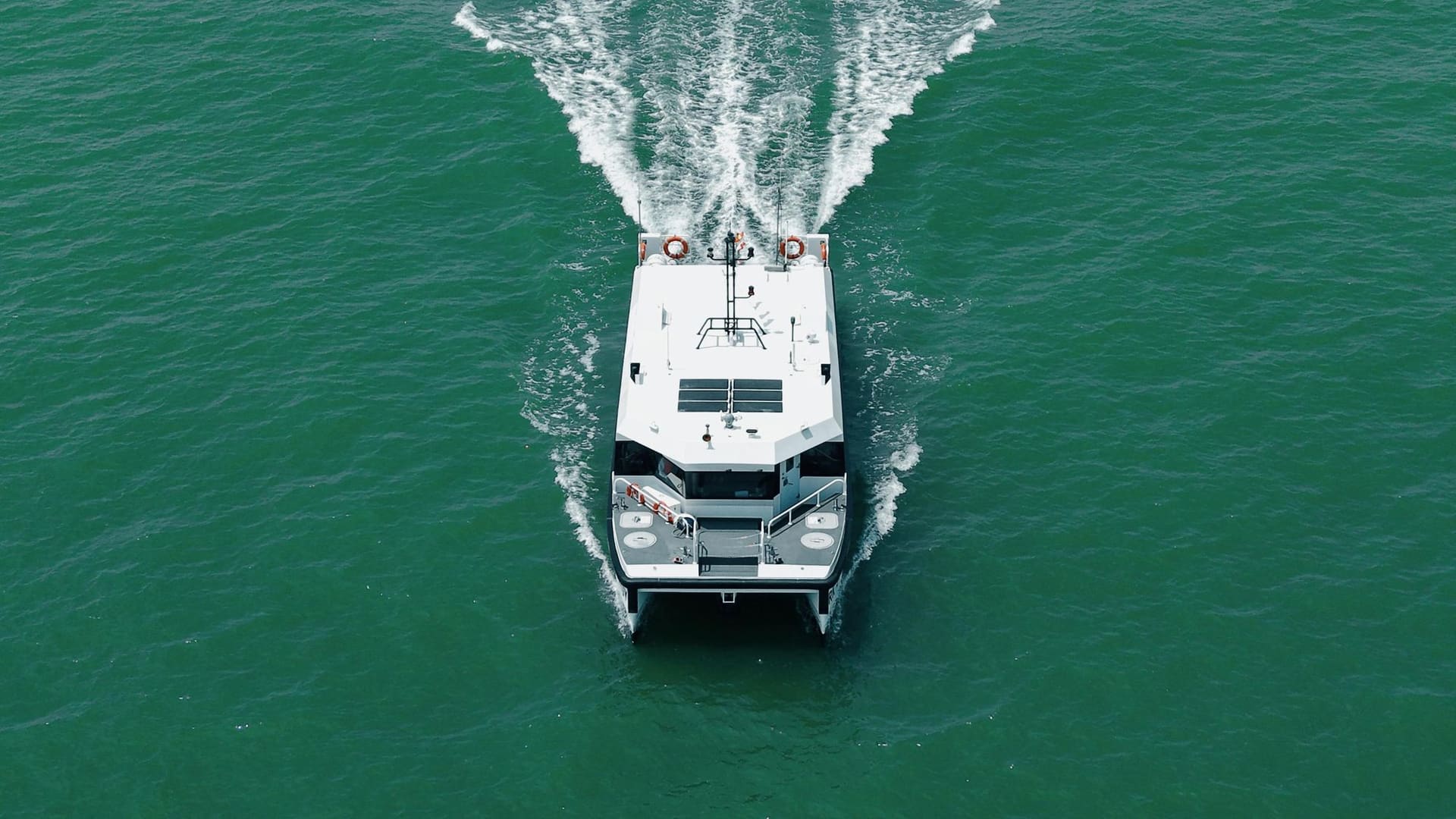 OBLUE E60 electric harbour craft running at speed, seen from astern
